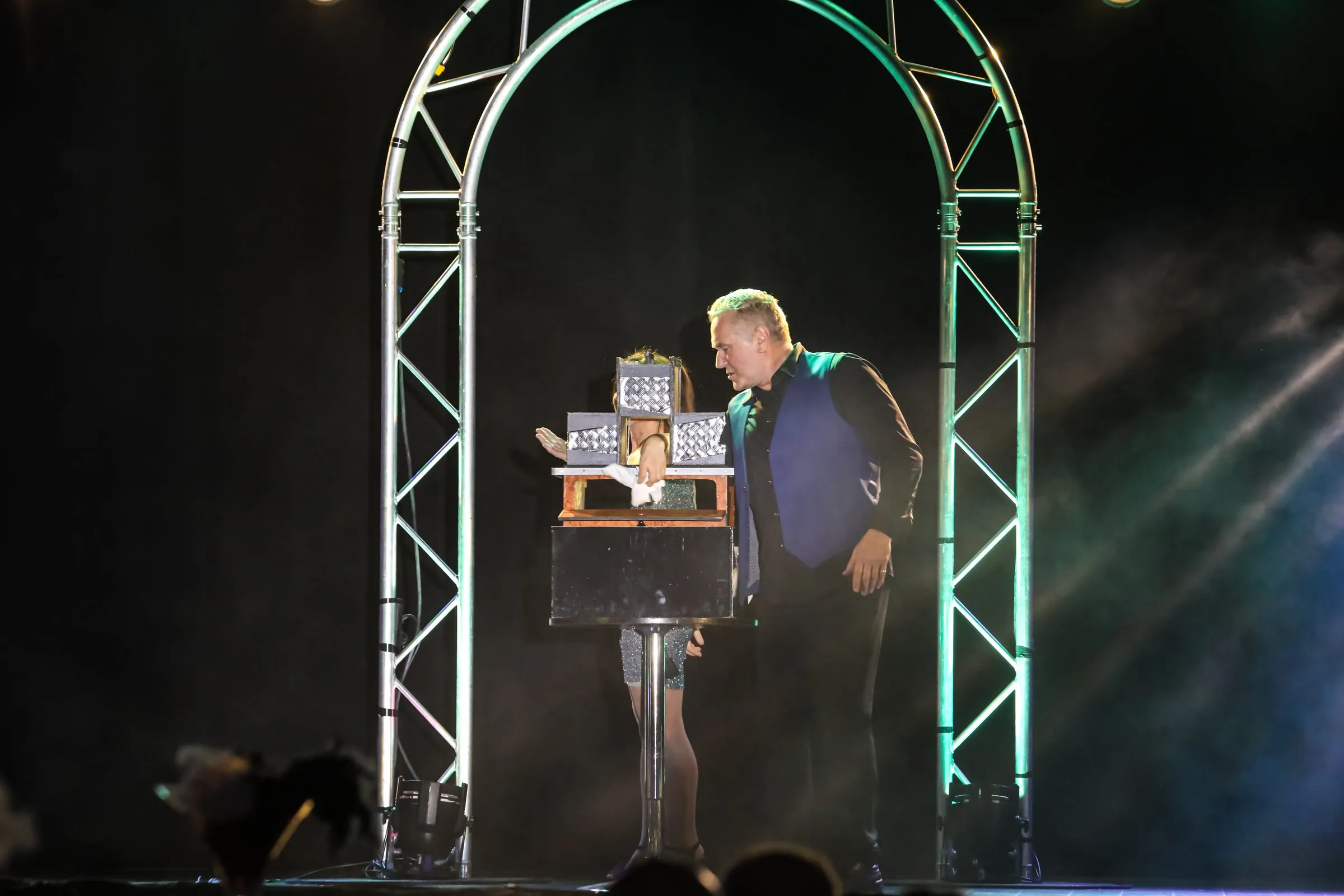 Mickaël Ross présente une illusion sur guéridon sous une arche lumineuse verte
