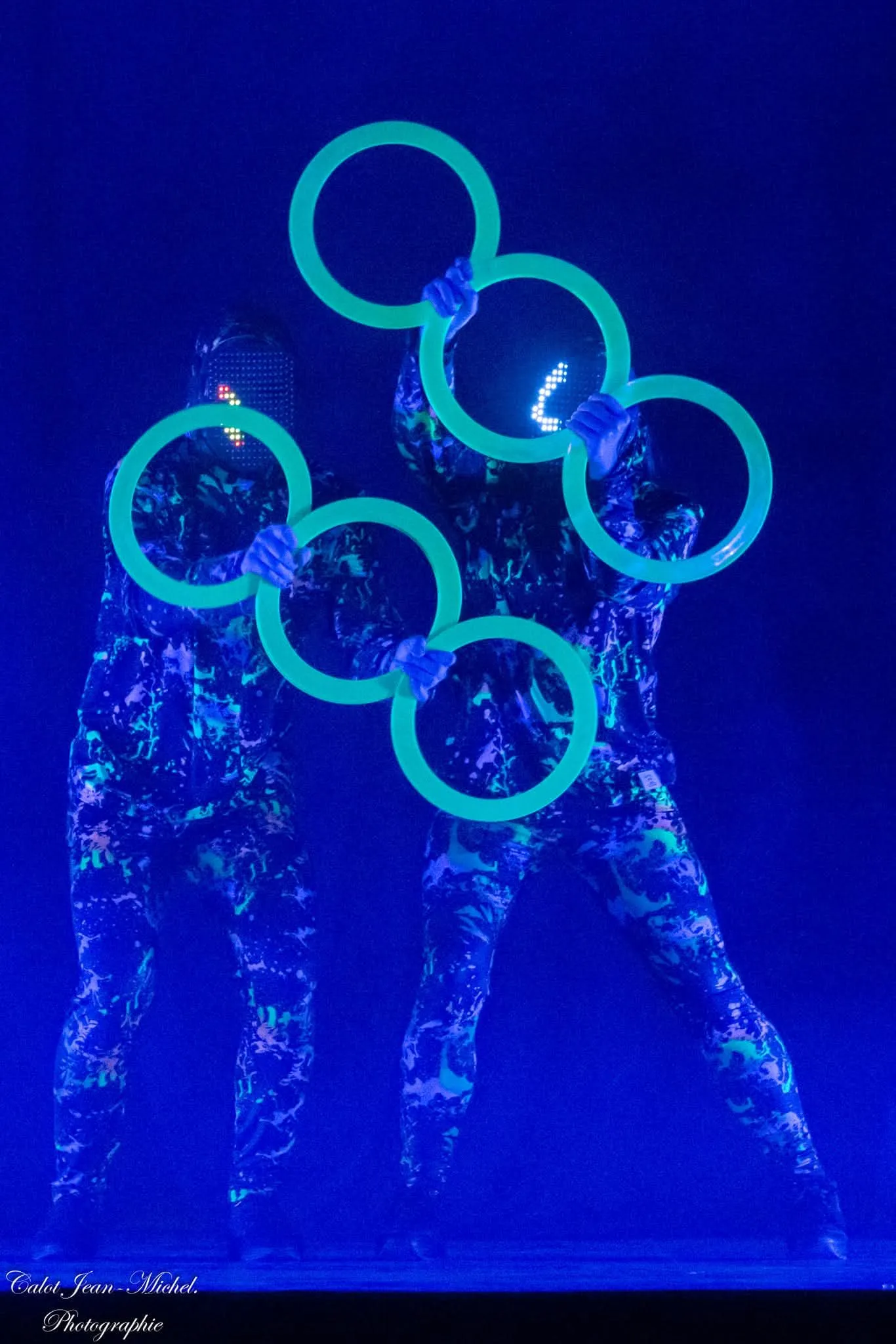 Duo de jongleurs aux anneaux lumineux dans un numéro en lumière UV
